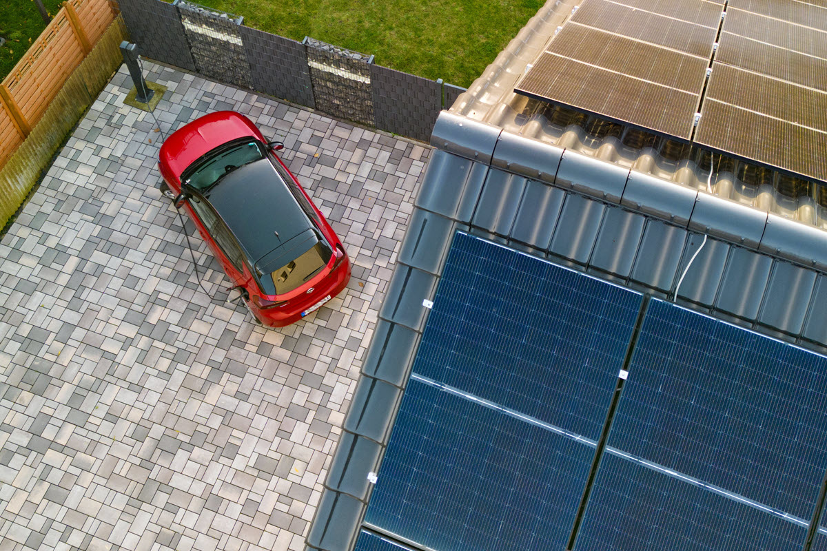 Bild von einem Hausdach mit Photovoltaikstromanlage und ein E-Auto