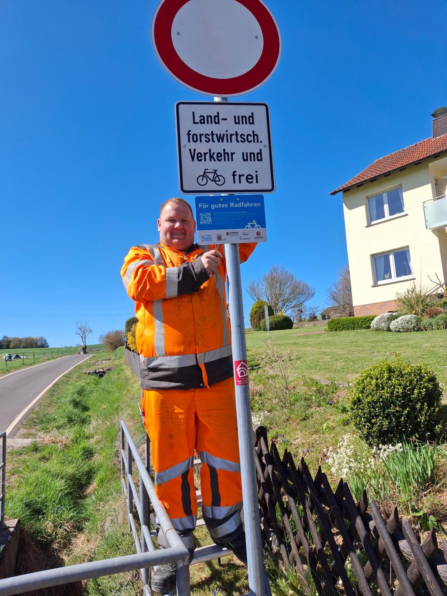 Herr Nico Brückmann vom Baubetriebshof der Gemeinde Fuldatal bringt die neuen Schilder in der Heinrichstraße im Ortsteil Simmershausen und in der Stockbreite im Ortsteil Ihringshausen an.