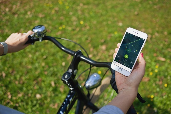 Fahrradfahrer mit Handy in der Hand, auf dem eine App gezeigt wird.