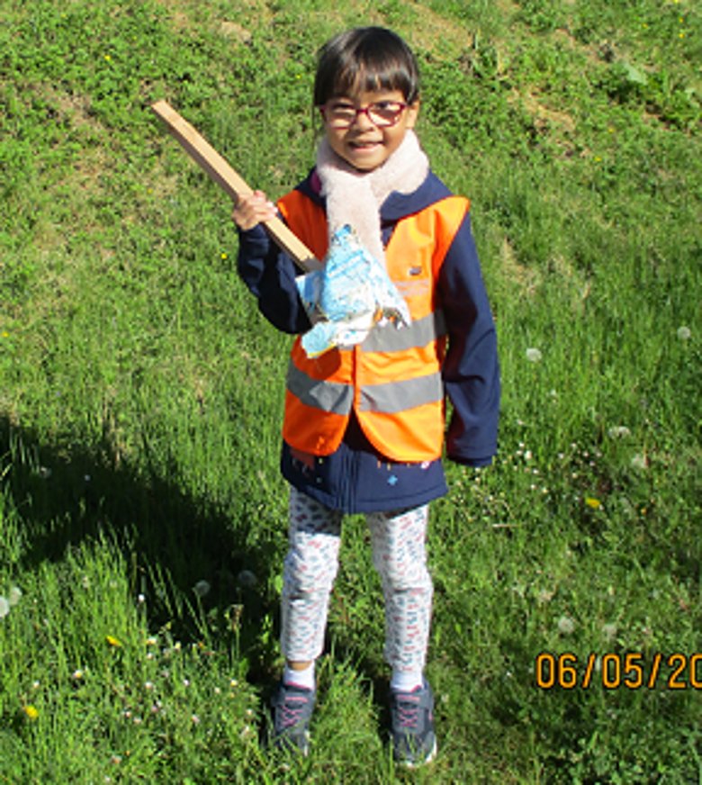 Das Bild zeigt, ein Vorschulkind mit Müllsammelzange in Aktion.