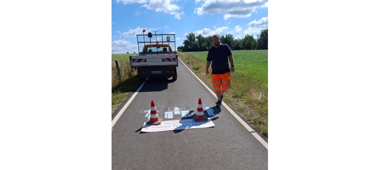 Herr Alexander Eckel vom Baubetriebshof der Gemeinde Fuldatal bringt das Pikto-gramm auf einem Radweg auf.