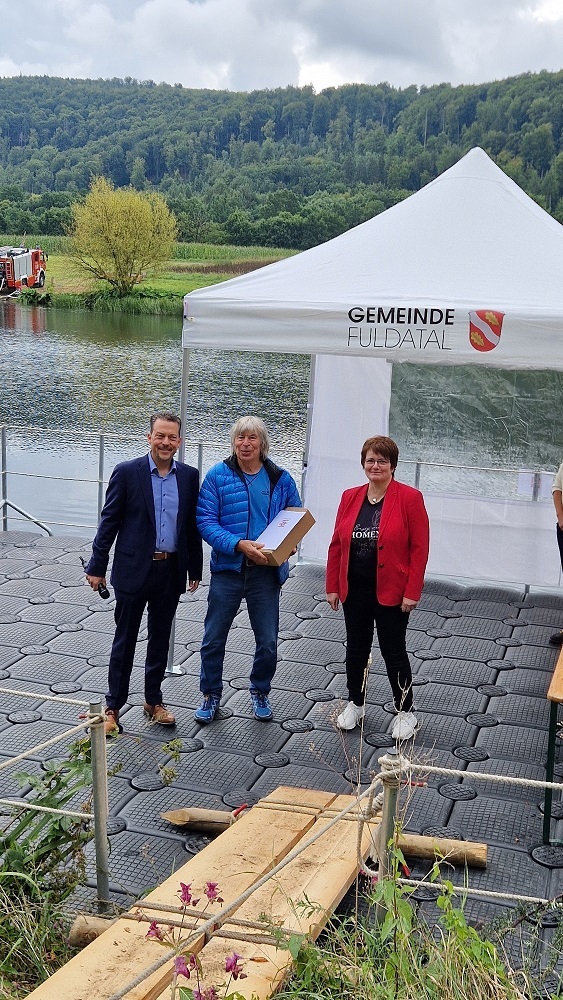 Bürgermeister Tore Florin überreicht die Dankesurkunde des Hessischen Ministers des Innern und für Sport im Rahmen der Sportlerehrung der Gemeinde Fuldatal am 23. August 2025 auf der Wasserbühne am Fuldaufer in Wilhelmshausen an den Sportcoach Bernd Quast im Beisein der Vorsitzenden der Gemeindevertretung Frau Stefanie Roß-Stabernack.