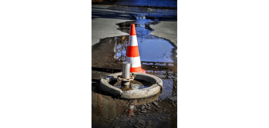 Wasseraustritt auf einer Straße mit Absperrung