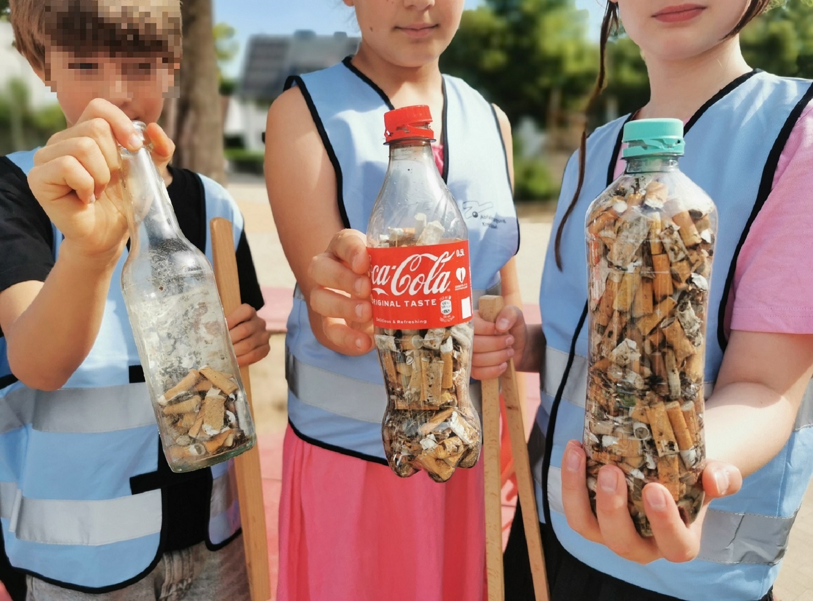 Kinder mit gesammelten Zigarettenkippen in Flaschen Kinder mit gesammelten Zigarettenkippen in Flaschen