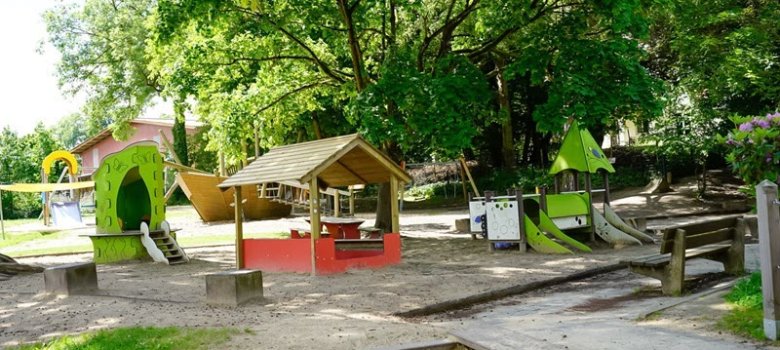 Bild des Außengeländes der Kita Simmershausen mit Sandkästen, Rutschen und Klettermöglichkeiten