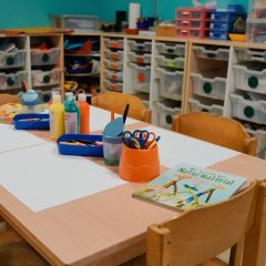 Bild eines Basteltisches mit Materialregalen im Hintergrund.