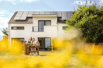 Familie vor Einfamilienhaus mit PV Anlage
